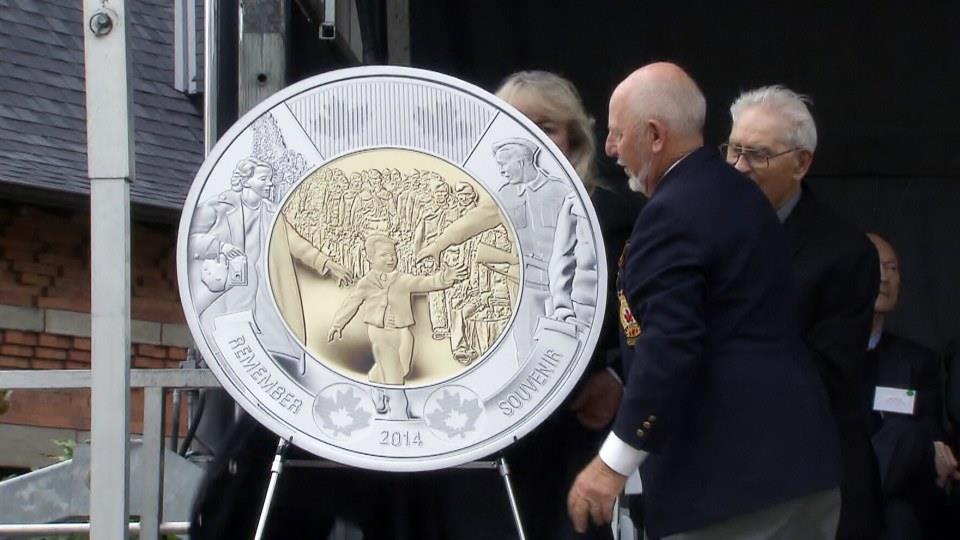 The two dollar coin minted to commemorate the anniversary of the Wait for me Daddy picture. The man in the foreground is the boy in the picture.
